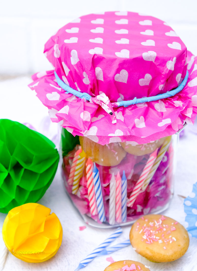 Bunte DIY Geschenkidee zum Geburtstag: Ein Glas bestücken mit Geburtstagskerzen, Luftballons, Papierschirmchen, Luftschlangen, mini Muffins und einem Gutschein | Geburtstag im Glas | Geschenke im Glas Ideen | waseigenes.com DIY Blog