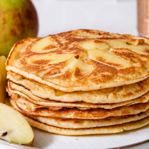 Fluffige Apfelpfannkuchen mit dünnen Apfelspalten auf einem Teller