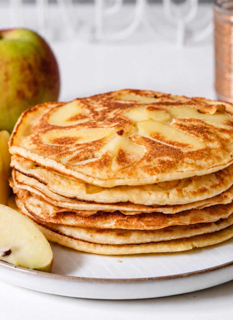 Fluffige Apfelpfannkuchen mit dünnen Apfelspalten auf einem Teller