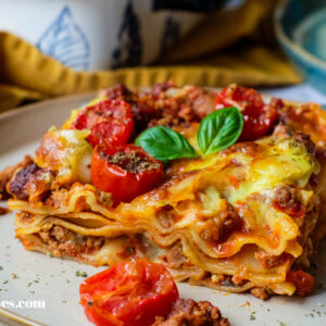 Saftige Lasagne al Forno auf einem Teller, gut erkennbare Schichten aus Bolognese, Béchamel und Pasta.