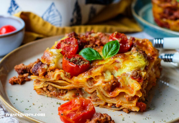Saftige Lasagne al Forno auf einem Teller, gut erkennbare Schichten aus Bolognese, Béchamel und Pasta.